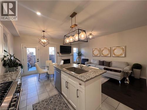 Kitchen featuring open floor plan, white cabinets, stainless steel appliances, a center island with sink, and a fireplace - 1165 West 5Th Street, Hamilton, ON - Indoor