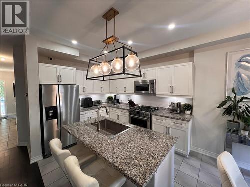 Kitchen with stainless steel appliances, a kitchen breakfast bar, white cabinets, and pendant lighting - 1165 West 5Th Street, Hamilton, ON - Indoor Photo Showing Kitchen With Upgraded Kitchen