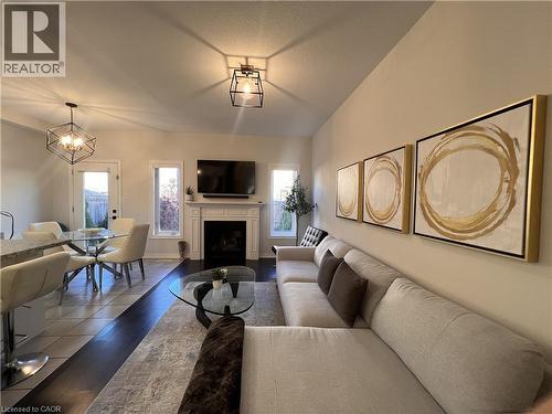 Living area featuring a fireplace with flush hearth, wood finished floors, and hanging lights - 1165 West 5Th Street, Hamilton, ON - Indoor Photo Showing Living Room With Fireplace