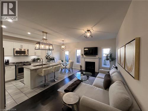 Living room featuring a fireplace, light tile patterned floors, and a chandelier - 1165 West 5Th Street, Hamilton, ON - Indoor With Fireplace