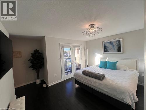 Bedroom with dark wood-style floors, access to exterior, a textured ceiling, and french doors - 1165 West 5Th Street, Hamilton, ON - Indoor Photo Showing Bedroom