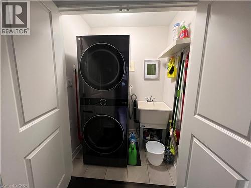 Laundry area featuring stacked washer / drying machine and light tile patterned flooring - 1165 West 5Th Street, Hamilton, ON - Indoor Photo Showing Laundry Room