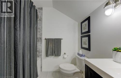 Full bathroom with vaulted ceiling, vanity, shower / bathtub combination with curtain, and light tile patterned floors - 306 Roxton Drive, Waterloo, ON - Indoor Photo Showing Bathroom