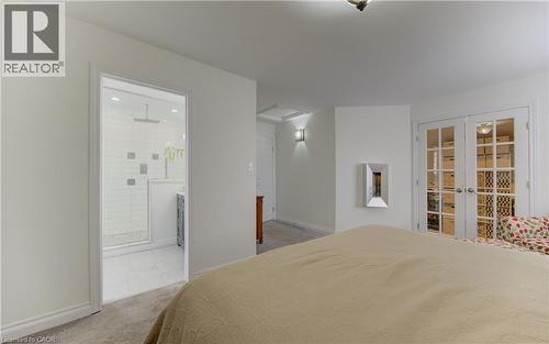 Bedroom with french doors, light colored carpet, and connected bathroom - 306 Roxton Drive, Waterloo, ON - Indoor Photo Showing Bedroom