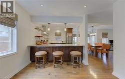 Bar area featuring light wood-type flooring, open shelves, freestanding refrigerator, electric range oven, and wood finish cabinets - 