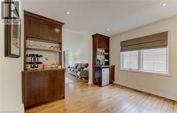 Bar featuring light wood-type flooring, open shelves, recessed lighting, and dark wood finish cabinetry - 
