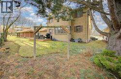 Back of property with a wooden deck, a lawn, and brick siding - 