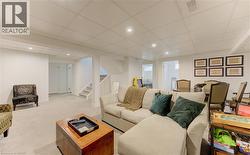 Living room with a paneled ceiling, recessed lighting, and light colored carpet - 
