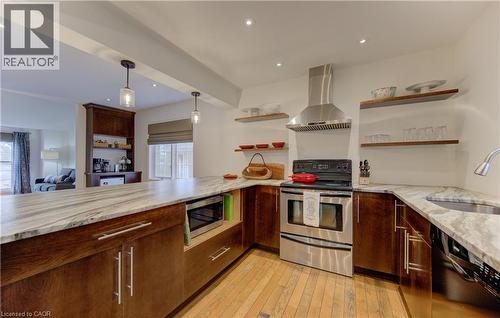 Kitchen with stainless steel appliances, ventilation hood, hanging light fixtures, light wood finished floors, and open shelves - 306 Roxton Drive, Waterloo, ON - Indoor Photo Showing Kitchen