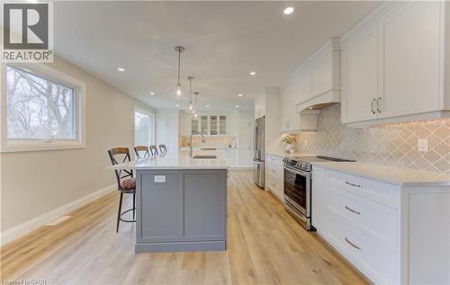 Dual tone kitchen with a breakfast bar area, stainless steel appliances, an island with sink, dual tone cabinetry, and glass insert cabinets - 395 Warrington Drive, Waterloo, ON - Indoor Photo Showing Kitchen With Upgraded Kitchen