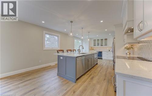Kitchen featuring stainless steel appliances, light wood-type flooring, a center island with sink, wine cooler, and tasteful backsplash - 395 Warrington Drive, Waterloo, ON - Indoor Photo Showing Kitchen