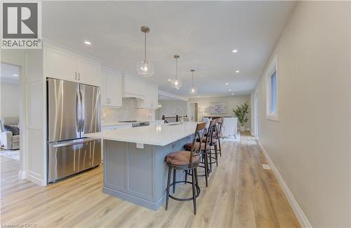 Two tone kitchen with stainless steel appliances, a large island, light wood-style flooring, a breakfast bar, and dual tone cabinetry - 395 Warrington Drive, Waterloo, ON - Indoor Photo Showing Kitchen With Stainless Steel Kitchen With Upgraded Kitchen