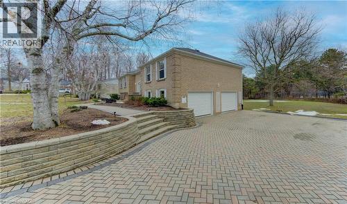 View of side of home with decorative driveway, a garage, and brick siding - 395 Warrington Drive, Waterloo, ON - Outdoor