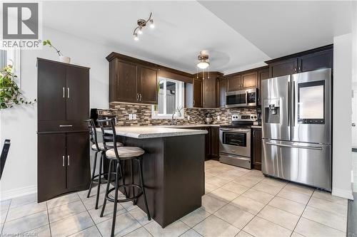 Kitchen with stainless steel appliances, dark wood finish cabinets, light tile patterned flooring, and light countertops - 160 Wallace Avenue S, Welland, ON - Indoor Photo Showing Kitchen With Upgraded Kitchen