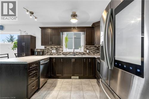 Kitchen with stainless steel appliances, dark wood finish cabinetry, a peninsula, light countertops, and backsplash - 160 Wallace Avenue S, Welland, ON - Indoor Photo Showing Kitchen With Double Sink With Upgraded Kitchen