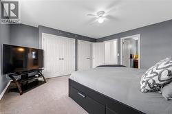 Bedroom with two closets, light colored carpet, a ceiling fan, and ensuite bath - 
