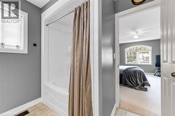 Bathroom featuring ensuite bathroom, light tile patterned floors, a ceiling fan, and shower / bath combo - 