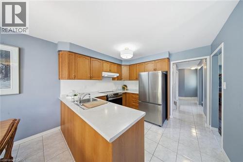 Kitchen featuring stainless steel appliances, wood finish cabinetry, light countertops, and light tile patterned floors - 200 Morrison Drive, Caledonia, ON - Indoor Photo Showing Kitchen