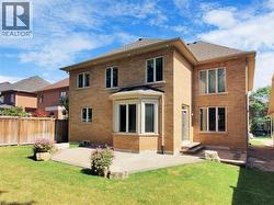 Back of property with brick siding, a patio, and a shingled roof - 