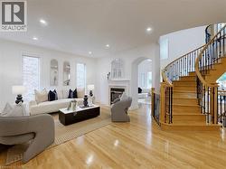 Living room featuring a glass covered fireplace, recessed lighting, wood finished floors, arched walkways, and stairs - 