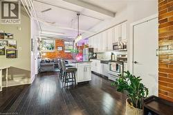 Kitchen featuring stainless steel appliances, a kitchen breakfast bar, white cabinetry, open floor plan, and dark wood-style floors - 