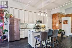 Kitchen with stainless steel appliances, light stone countertops, brick wall, pendant lighting, and a breakfast bar - 