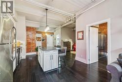 Kitchen with stainless steel appliances, a kitchen breakfast bar, white cabinets, pendant lighting, and brick wall - 