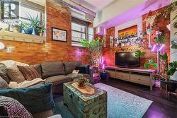 Living area with brick wall and dark wood-style flooring - 
