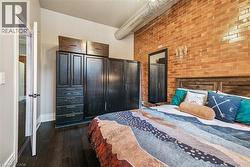 Bedroom featuring brick wall and dark wood-style floors - 