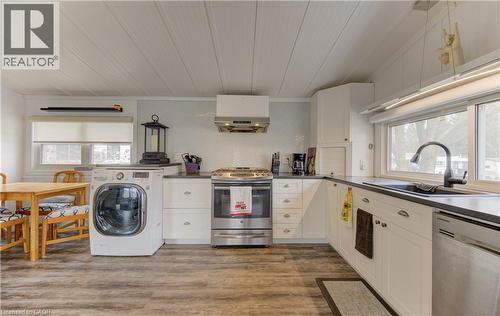 Kitchen with plenty of natural light, stainless steel appliances, washer / dryer, and white cabinetry - 580 Beaver Creek Road Unit# 11, Waterloo, ON - Indoor Photo Showing Laundry Room