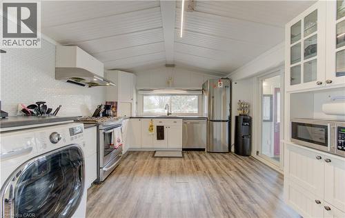 Kitchen featuring washer / dryer, white cabinetry, glass insert cabinets, stainless steel appliances, and light wood-style floors - 580 Beaver Creek Road Unit# 11, Waterloo, ON - Indoor Photo Showing Laundry Room