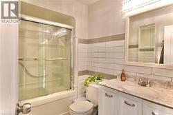 Bathroom with vanity, enclosed tub / shower combo, tasteful backsplash, and tile walls - 