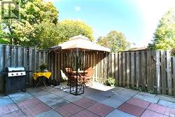 Fenced backyard featuring a gazebo, a patio, and a grill - 