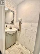 Half bathroom featuring vanity, a textured wall, and tile walls - 