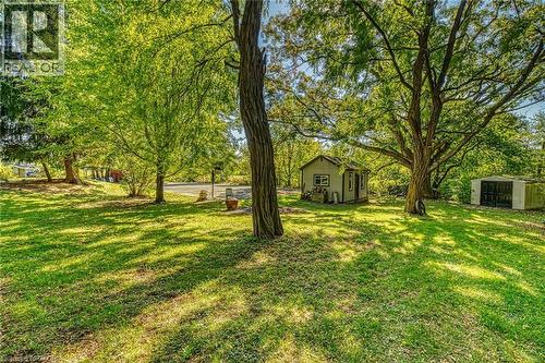 View of grassy yard featuring a storage shed and view of scattered trees - 5590 Blind Line, Burlington, ON - Outdoor