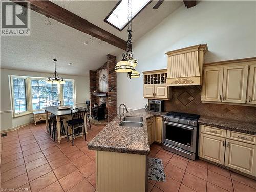 Kitchen featuring cream cabinets, stainless steel gas range oven, a peninsula, and light tile patterned flooring - 5590 Blind Line, Burlington, ON - Indoor Photo Showing Kitchen With Double Sink
