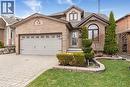 View of front of house with an attached garage, decorative driveway, brick siding, a shingled roof, and a front lawn - 40 Artistic Boulevard, Hamilton, ON  - Outdoor With Facade 