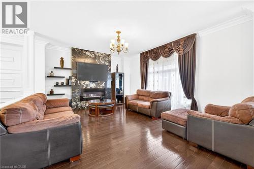 Living room featuring ornamental molding, a premium fireplace, suspended lighting, and wood-type flooring - 182 Irwin Avenue, Hamilton, ON - Indoor Photo Showing Living Room