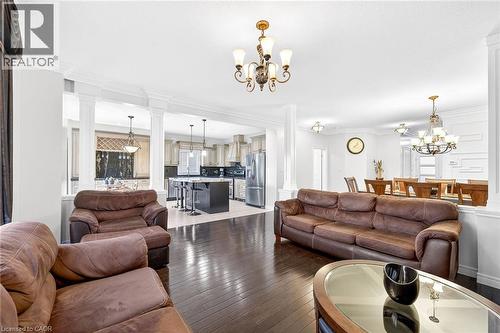 Living room with decorative columns, hanging lights, ornamental molding, and light wood-style floors - 182 Irwin Avenue, Hamilton, ON - Indoor Photo Showing Living Room