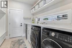 Laundry room featuring separate washer and dryer, light tile patterned flooring, and cabinet space - 