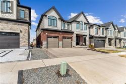 View of front of home featuring an attached garage, concrete driveway, stucco siding, and stone siding - 