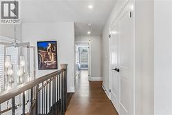 Hallway featuring dark wood-type flooring, an upstairs landing, and recessed lighting - 
