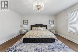 Bedroom with dark wood-style floors and hanging lights - 