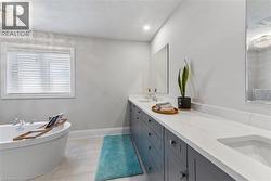 Full bath featuring a freestanding tub, double vanity, a textured ceiling, light tile patterned floors, and recessed lighting - 