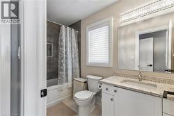 Bathroom featuring vanity, shower / bath combo, light tile patterned floors, and a textured ceiling - 