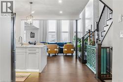 Kitchen featuring white cabinetry, open floor plan, hanging light fixtures, dark wood-style flooring, and light stone counters - 