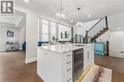 Kitchen with light wood-style floors, a center island with sink, white cabinetry, and light stone countertops - 