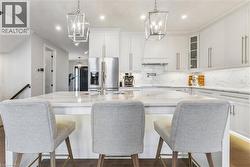 Kitchen featuring white cabinetry, light stone counters, and stainless steel refrigerator with ice dispenser - 