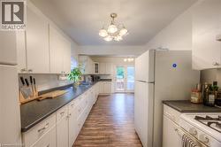Kitchen with white cabinetry, dark countertops, a chandelier, and dark wood-type flooring - 