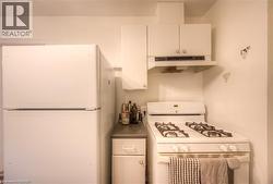 Kitchen featuring white appliances, white cabinetry, and dark countertops - 